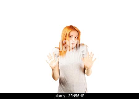 Anti harassment defensive attitude concept. Beautiful redhead young woman doing BACK OFF gesture. Attractive female with red hair saying stop via body Stock Photo