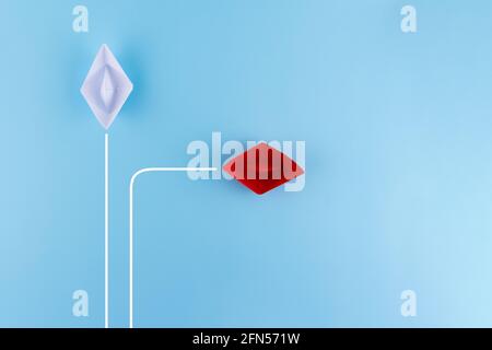 Red paper ship pointing in new direction on blue background, New normal, Business for innovative solution concept. Stock Photo