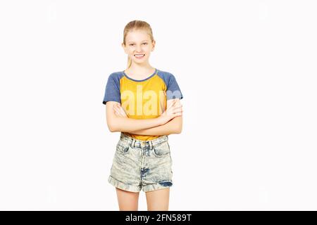 Young beautiful teenage girl with blond hair in ponytail wearing yellow baseball t-shirt with blue sleeves. Pretty female smiling with folded hands st Stock Photo