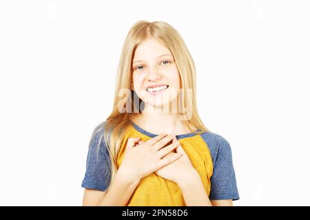 Young beautiful pleased teenage girl with blond hair in wearing yellow baseball t-shirt with blue sleeves. Pretty girl smiling, hand palms on chest, s Stock Photo