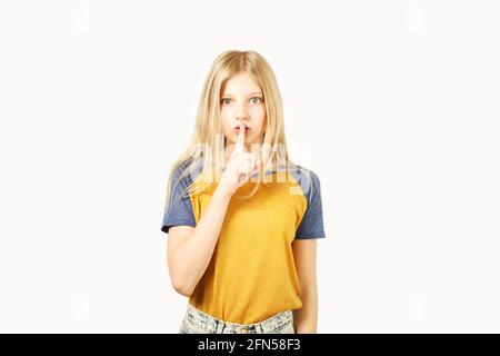 Young beautiful indecisive teenage girl with blond hair wearing yellow baseball t-shirt with blue sleeves, showing shush, don't tell anyone gesture wi Stock Photo