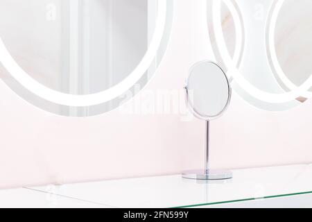 Round mirrors with illuminated reflections, modern design pastel blue and pink stylized in a beauty studio salon. Stock Photo