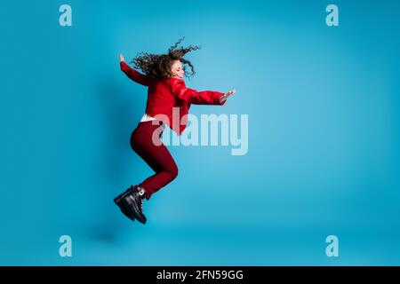 Full size profile photo of hooray girl jump wear red jacket trousers boots isolated on blue background Stock Photo