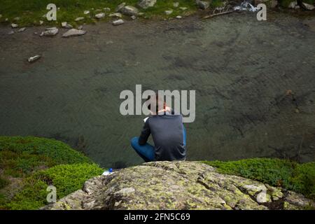 A teenager reading a book above a mountain stream in the French Pyrenees Stock Photo