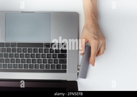 Close-up photo of a type-c usb hub that connected to laptop by a female hand. Minimalistic Stock Photo