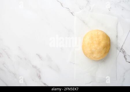 Ball of dough for baking on white marble background with dusting of flour. Recipe step by step. Selective focus. Stock Photo