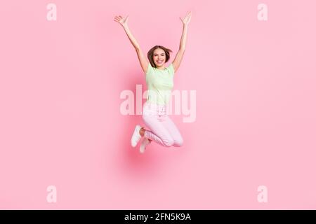 Full body portrait of astonished pretty person jump raise arms palms isolated on pink color background Stock Photo