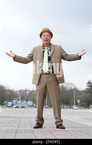 handsome man in his 50s in a suit from the 1980s and colorful shirt gestures like a classical gangster Stock Photo