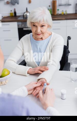 elderly woman looking at nurse doing injection of insulin on blurred background Stock Photo