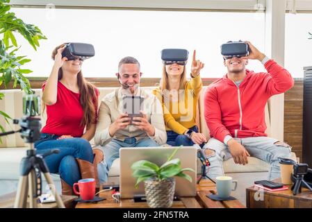 Young students wearing virtual reality glasses indoor. five people having fun with new technology vr headset goggles. friends live streaming.new mania Stock Photo