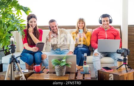 Addicted multicultural group of friends ignoring live communication while chatting in social networks or smartphones using wireless 5G internet home Stock Photo