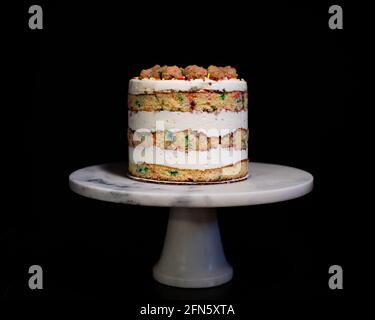 Rainbow Sprinkle Birthday Cake on White Marble Cake Stand Stock Photo