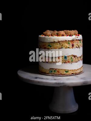 Rainbow Sprinkle Birthday Cake on White Marble Cake Stand Stock Photo