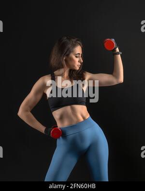 Brunette girl doing biceps with dumbbells Stock Photo