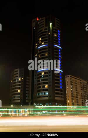 Traffic lighttrails at night in front of a dark modern building Stock Photo