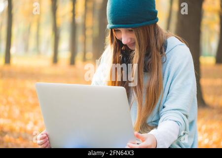 Cute girl working on laptop in autumn park Stock Photo