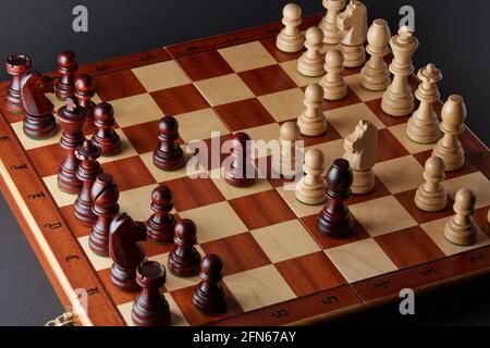 Classic Wooden Tournament chess set on black background. Chessboard with pieces. Arrangement of the pieces stems from an opening known as Queen's Gamb Stock Photo