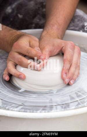 Potters hands skilfully centering / centre the clay before hand throwing a ceramic thrown hand made vase pot on a turning wheel. England. UK (123) Stock Photo