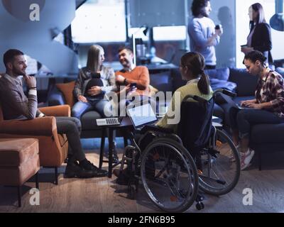 Young woman in wheelchair working on laptop at office. Getting an education at home concept Stock Photo