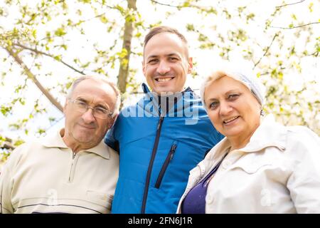 Adult son with his elderly parents outdoors in a natural setting. Stock Photo