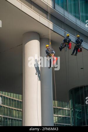 milan italy march 29 2021: skilled glass cleaners who lower themselves with slings from above Stock Photo