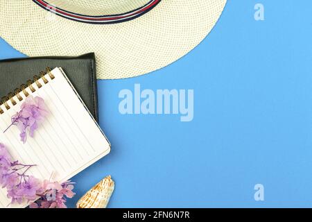 Summer vacation notebook, diary concept, tropical hat and sea shells on blue background, top view and flat lay Stock Photo