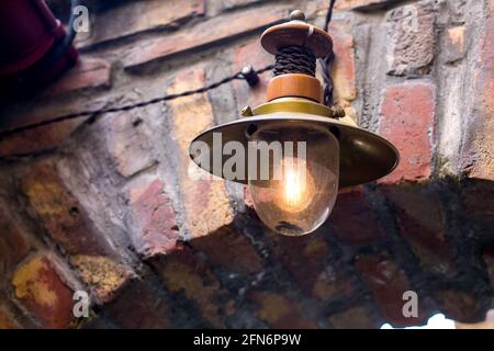 retro street light lantern on brick wall with edison electric lamp, decorative architectural element in old style close-up. Stock Photo