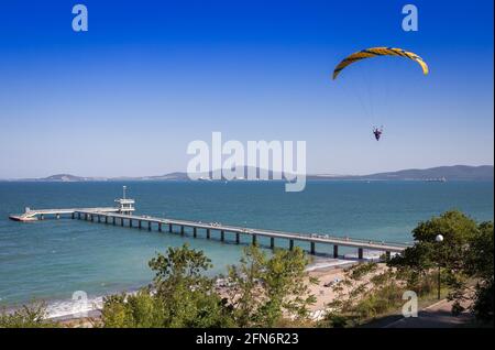 Paraglider flies against blue sky Stock Photo