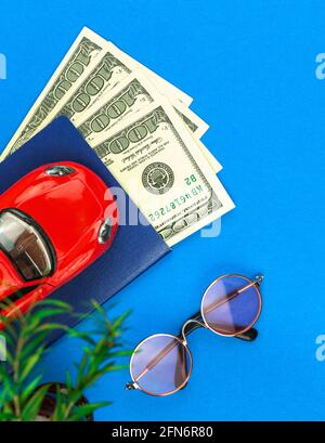 Trip and travel planning flat lay composition, red toy car and money on a blue background, top view Stock Photo