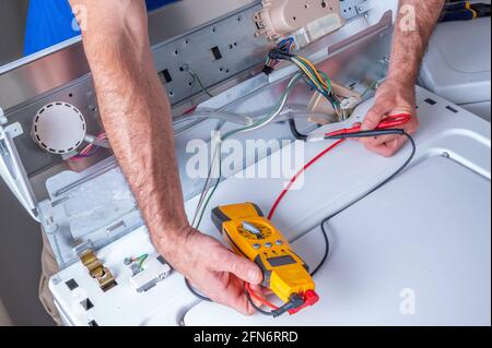 Hands of an appliance technician troubleshooting or repairing a washing machine Stock Photo