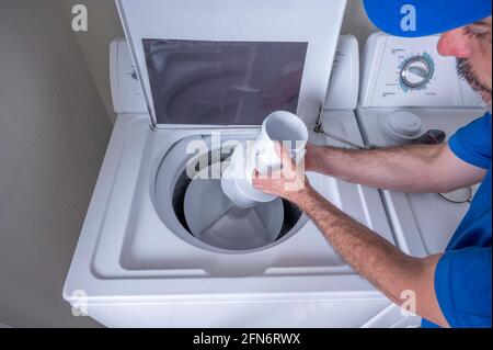 Appliance repair service of hands removing a agitator from a residential washing machine Stock Photo
