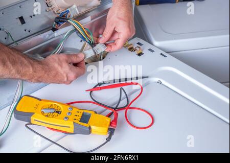 Connecting and electrical circuit on a washing machine, troubleshooting and repair, volt meter tool sitting on top load washer Stock Photo