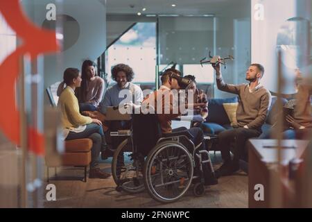 Disabled businessman in a wheelchair at work in modern open space coworking office with team using virtual reality googles drone assistance simulation Stock Photo