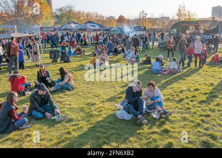 Kazan, Russia - October 03, 2020: Residents relax, sit and lie on the lawn in the city park, around which there are many mobile barbecue restaurants. Stock Photo