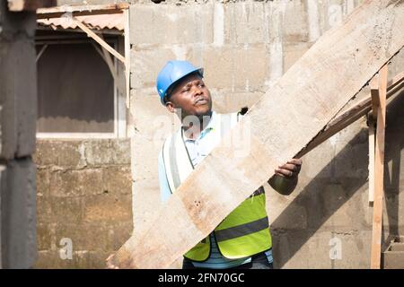 a carpenter carrying wood on site Stock Photo