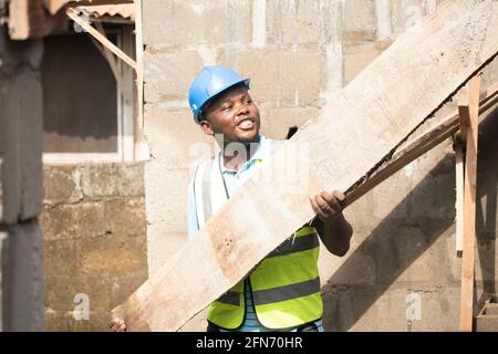 a carpenter carrying wood on site Stock Photo