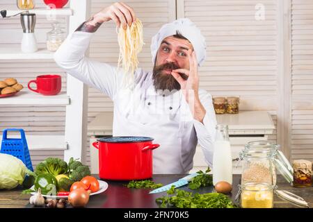 Bearded chef with spaghetti. Noodles. Male Cook in uniform with perfect sign. Stock Photo