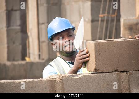 an african bricklayer laying bricks and holding a trowel Stock Photo