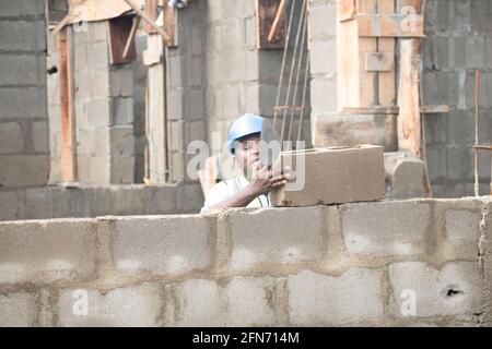 an african bricklayer laying bricks and holding a trowel Stock Photo