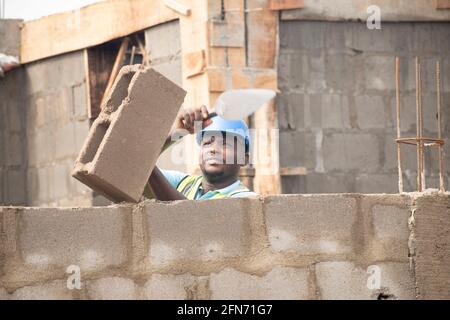an african bricklayer laying bricks and holding a trowel Stock Photo