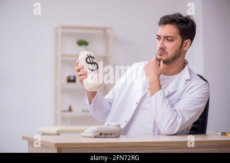 Young doctor holding moneybag in remuneration concept Stock Photo