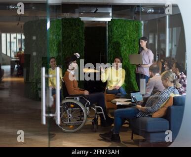 Disabled businessman in a wheelchair at work in modern open space coworking office with team using virtual reality googles drone assistance simulation Stock Photo