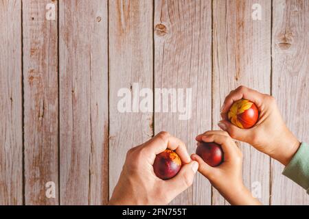 Top down flat lay view on easter eggs painted in hands of unknown people holding above wooden background with copy space Stock Photo