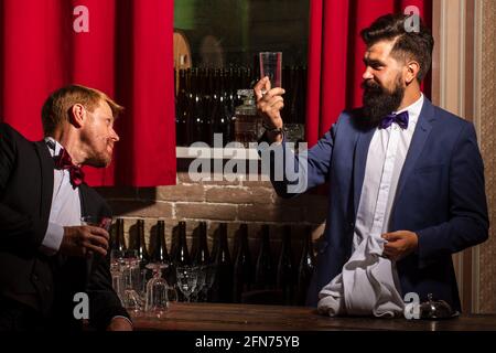 Barmen and customer. Alcohol beverage. Barman at counter. Hipster in bar. Old traditional whiskey drink. Gentlemans beverage. Stock Photo