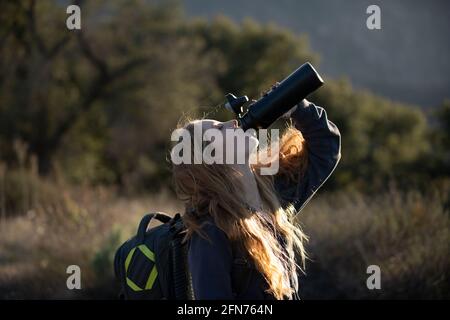 Woman traveler drink water. Female hiker with backpack at mountain. Girl hiking a hill at panoramic point. Backpacking tourism concept Stock Photo