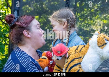 Lynwood, Washington, USA.  Four year old girl and her mother hugging and being affectionate.  (MR) Stock Photo