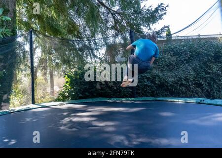 Lynwood, Washington, USA.  Seventeen year old boy bouncing mid-air on a trampoline in his backyard.  (MR) Stock Photo