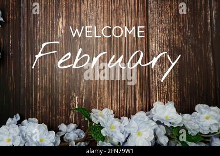 Welcome February text and blue flower decoration on wooden background Stock Photo