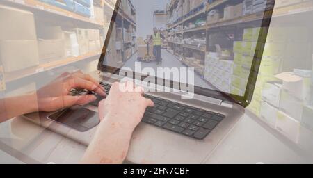 Composition of man using laptop over stacked up boxes in warehouse Stock Photo
