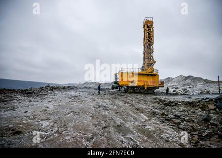 Belarus. November 2014 - Special chisel machine tools for drilling of deep chinks for carrying out of explosive works in career. Worker in overalls. Production Extraction of granite stone by quarry machines in Mikashevichi. Stock Photo